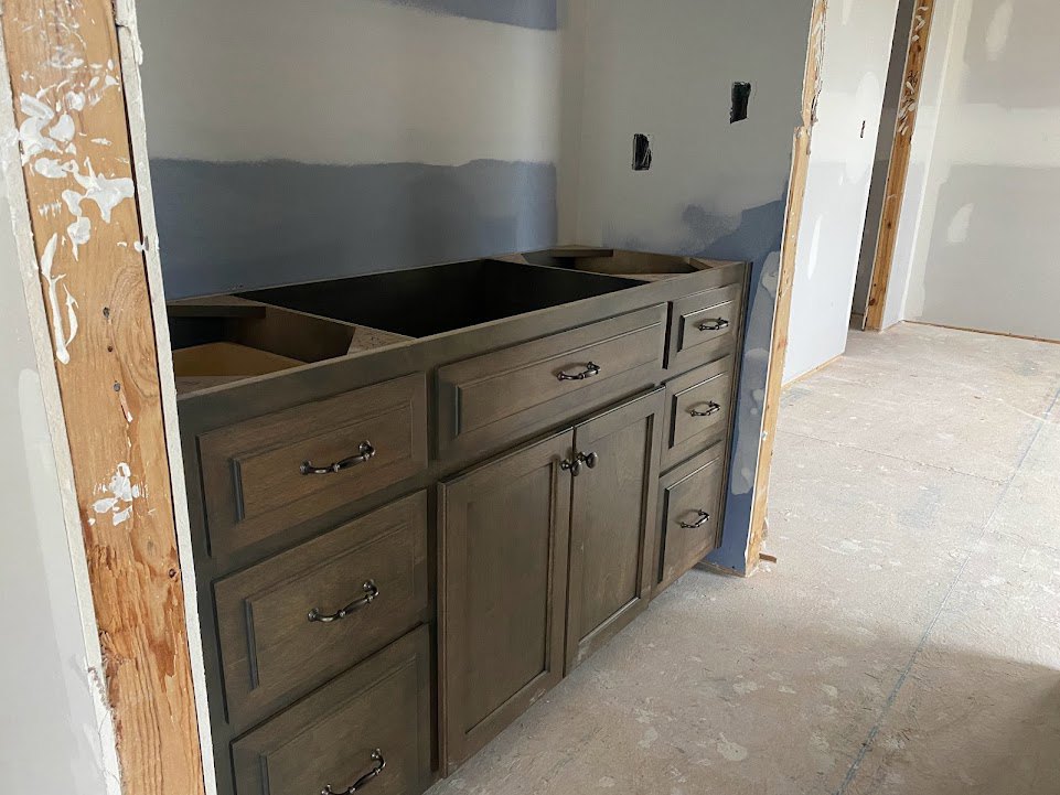 White shaker kitchen cabinets with brushed metal handles, quartz countertop, stainless steel sink, and light wood flooring