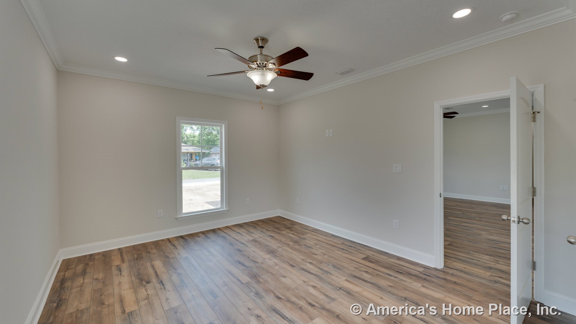 Bedroom with wood-look plank flooring, ceiling fan with integrated light, large single window, white trim and baseboards, recessed ceiling lights, open doorway to adjacent room