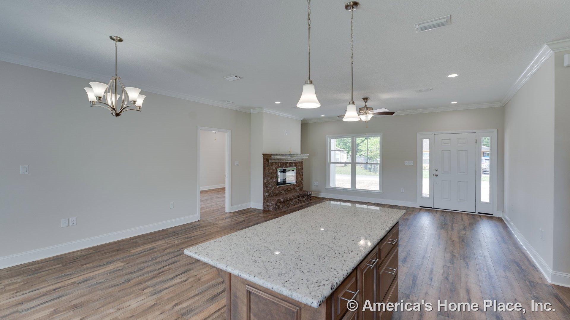 Open floor plan living area with brick fireplace and mantel, wood-look plank flooring, granite kitchen island, multiple pendant lights, large front window, white crown molding, and