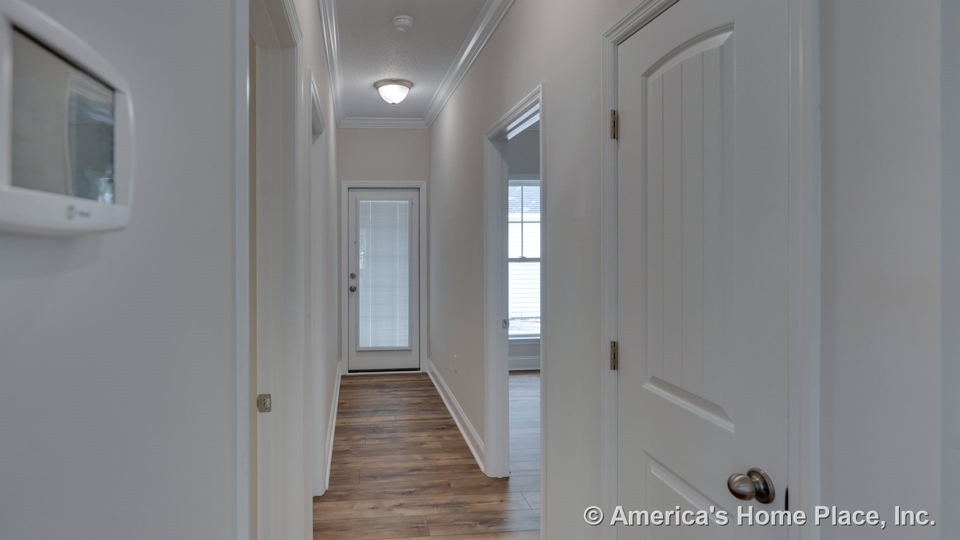 Hallway with wood-look plank flooring, white crown molding and trim, glass exterior door with built-in blinds, panel interior doors, flush mount ceiling light, and neutral wall