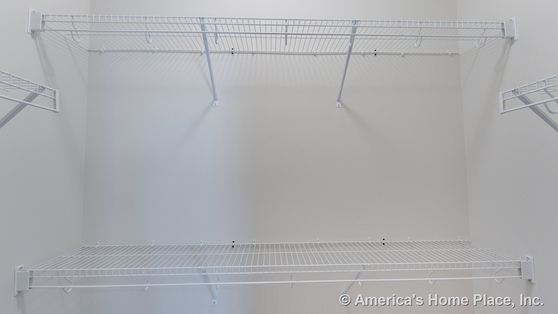 Walk-in closet with built-in white wire shelving on three walls, wall-mounted metal shelf brackets, open storage system, and neutral painted walls.