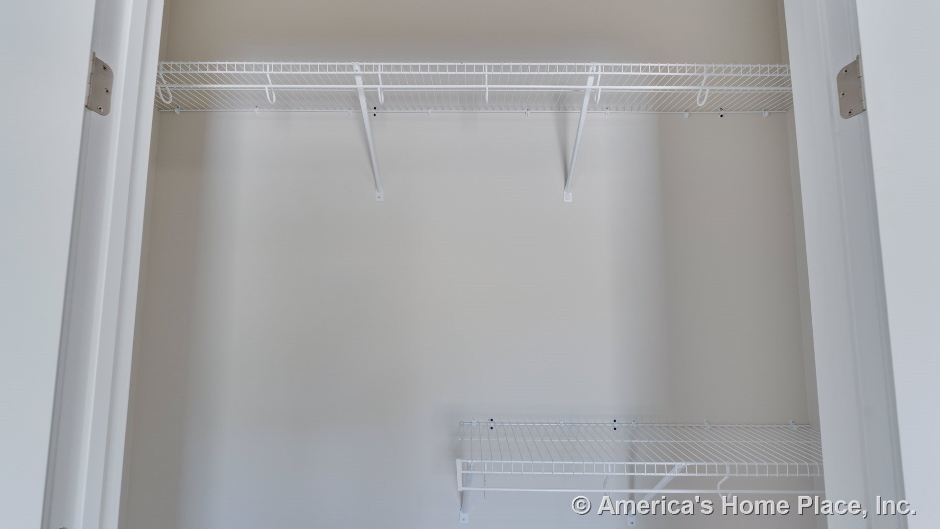 Built-in white wire shelving with metal brackets lines the interior closet space, featuring neutral wall paint, white trim, and double closet doors for organized storage.