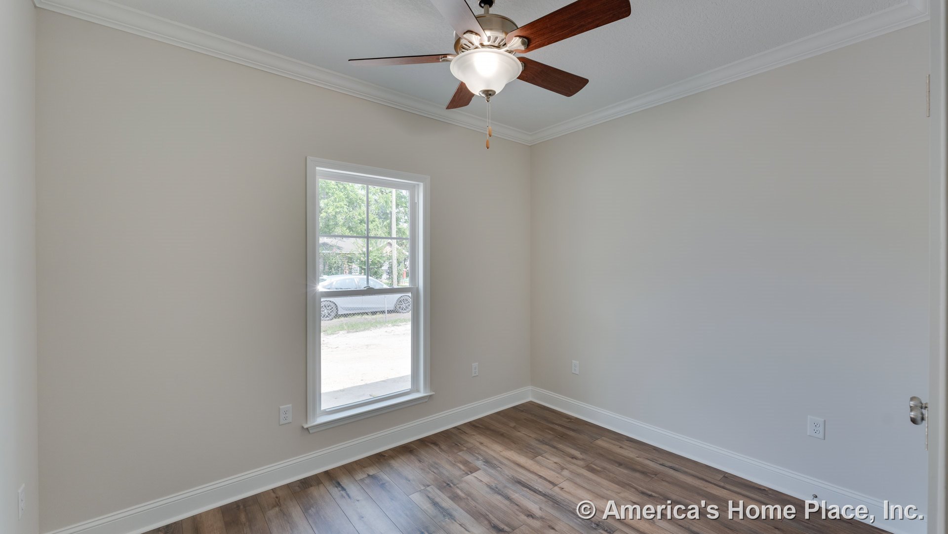 Small bedroom with crown molding, wood-look plank flooring, single window with white casing, ceiling fan and light fixture, neutral painted walls, white baseboards, visible door