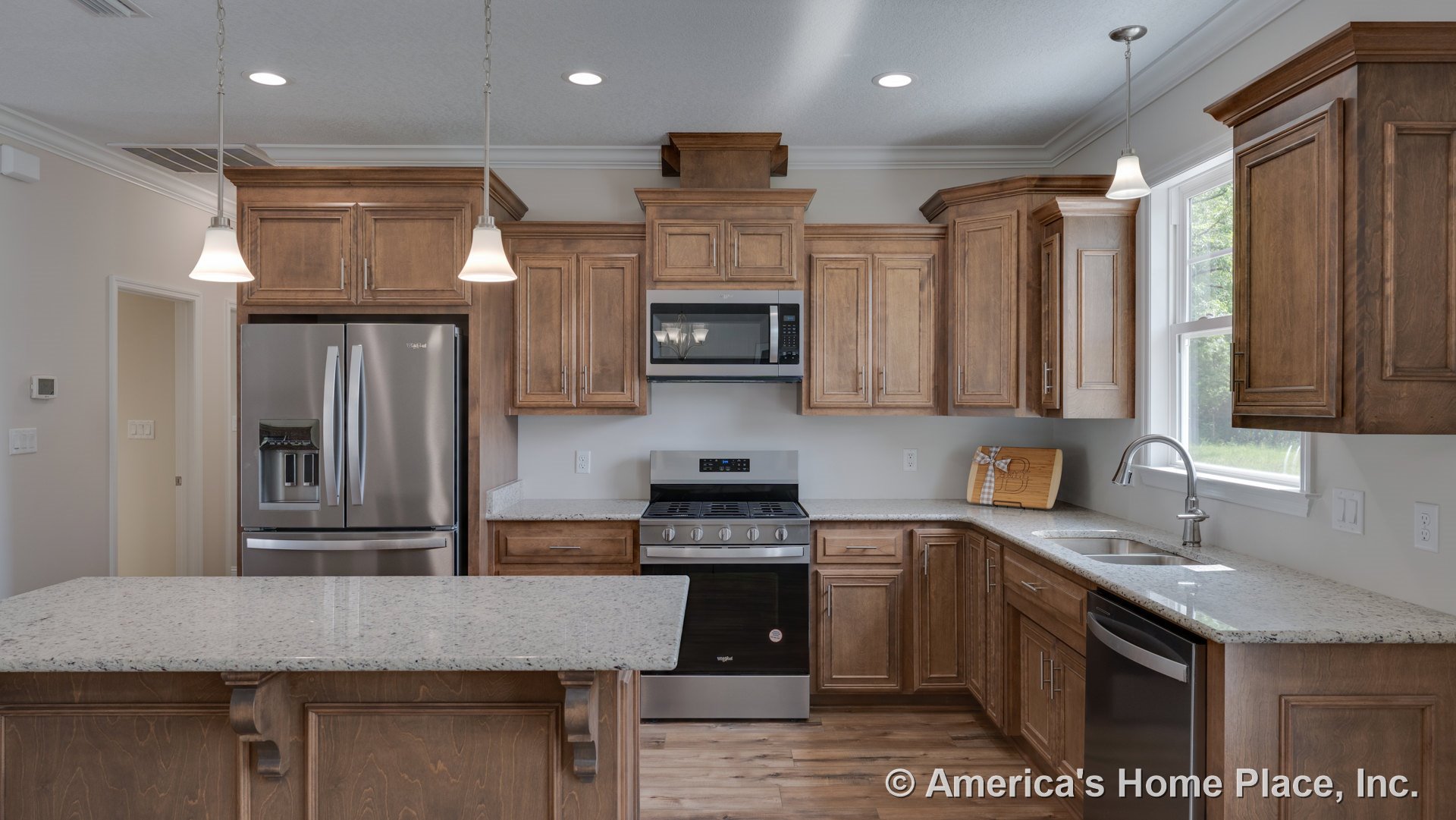 Wood cabinetry kitchen with granite countertops, stainless steel refrigerator, gas range and microwave, pendant lights, double sink beneath window, dishwasher, and hardwood