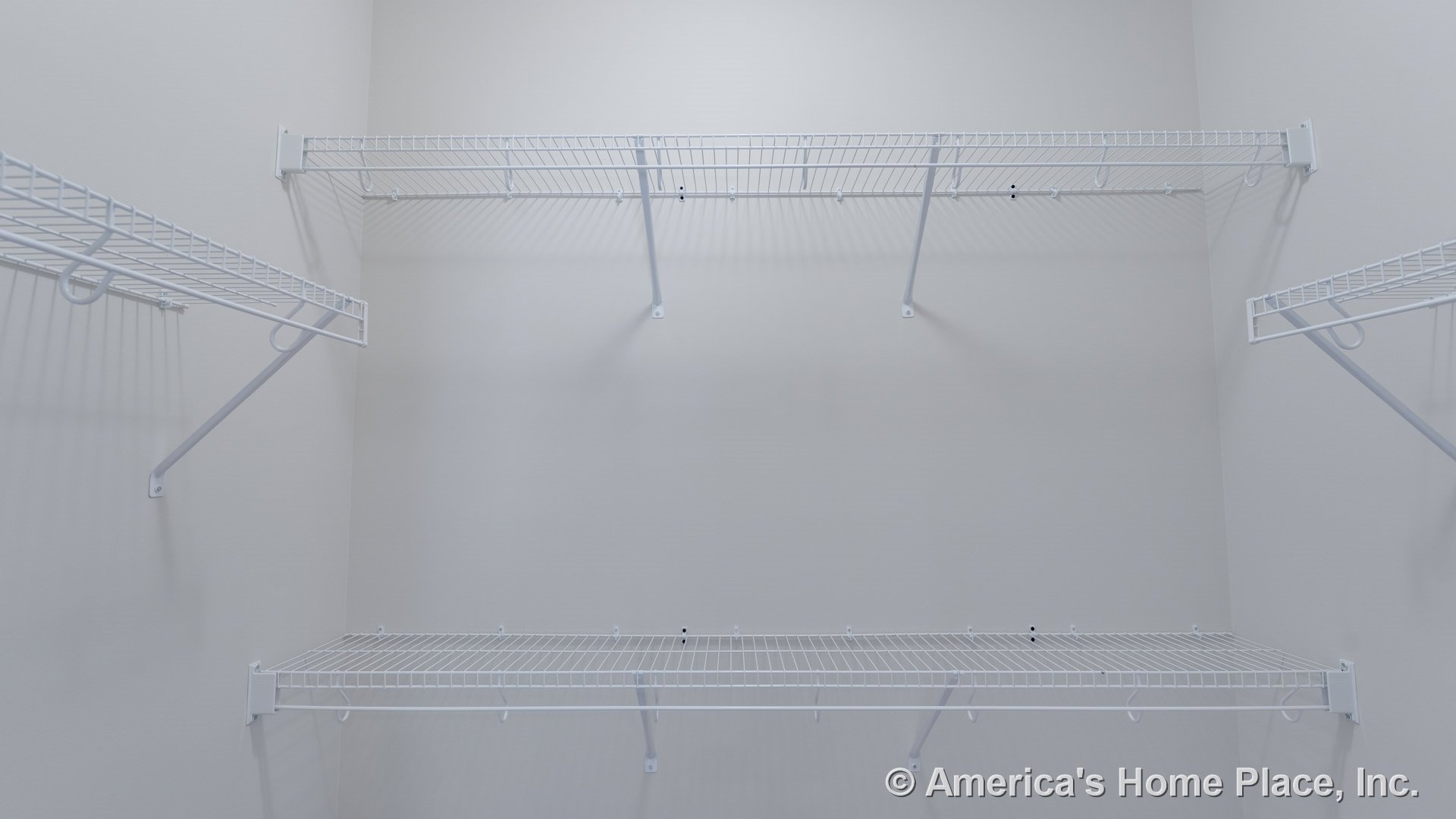 Walk-in closet with multiple white wire shelving units mounted on light-painted walls, featuring built-in storage and metal shelf brackets for organization.