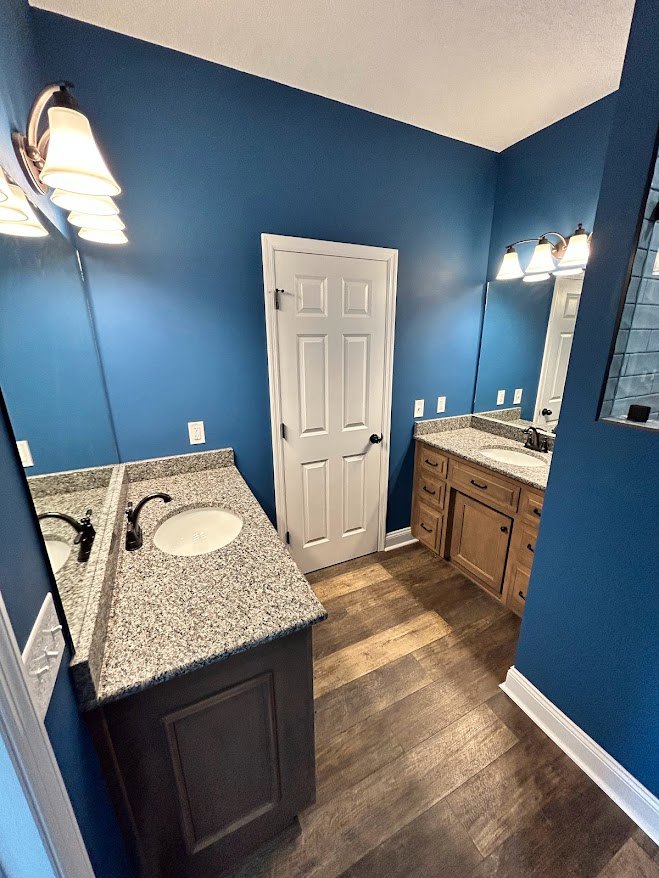Bathroom with blue painted walls, marble countertop, white undermount sink, tile flooring, and light wood cabinetry with drawers