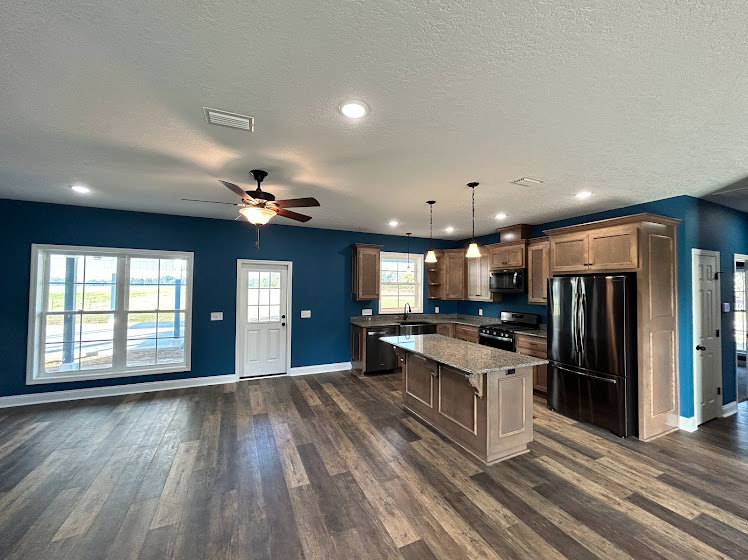 Kitchen with hardwood flooring, white cabinetry, stainless steel refrigerator, and ceiling fan with light fixture