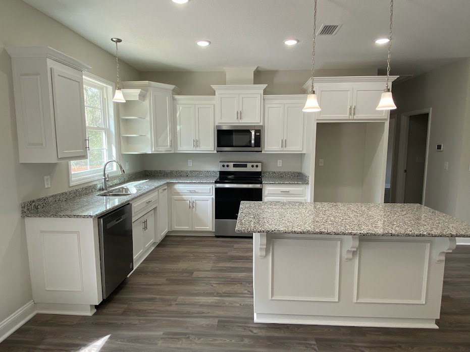 Granite countertops with white cabinetry, black dishwasher, stainless steel microwave, and sink in a modern kitchen