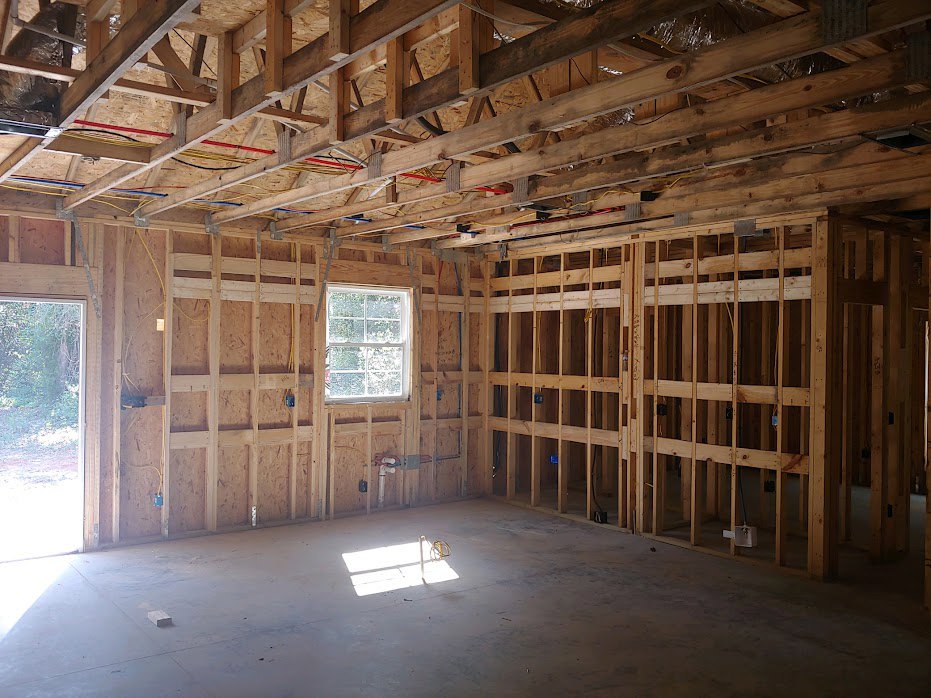 Exposed wood ceiling beams, white-framed window, light streaming onto neutral walls, hardwood flooring