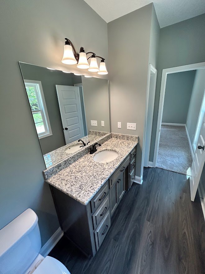 Bathroom with marble countertop, rectangular mirror above sink, white tile walls, and toilet visible in corner