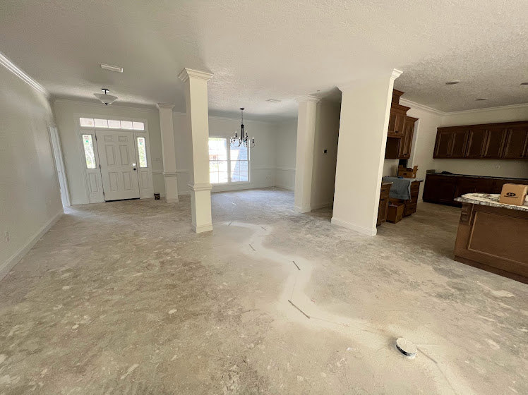 White ceiling and walls, white door, white pillar with natural light, light-colored flooring, minimal furnishings
