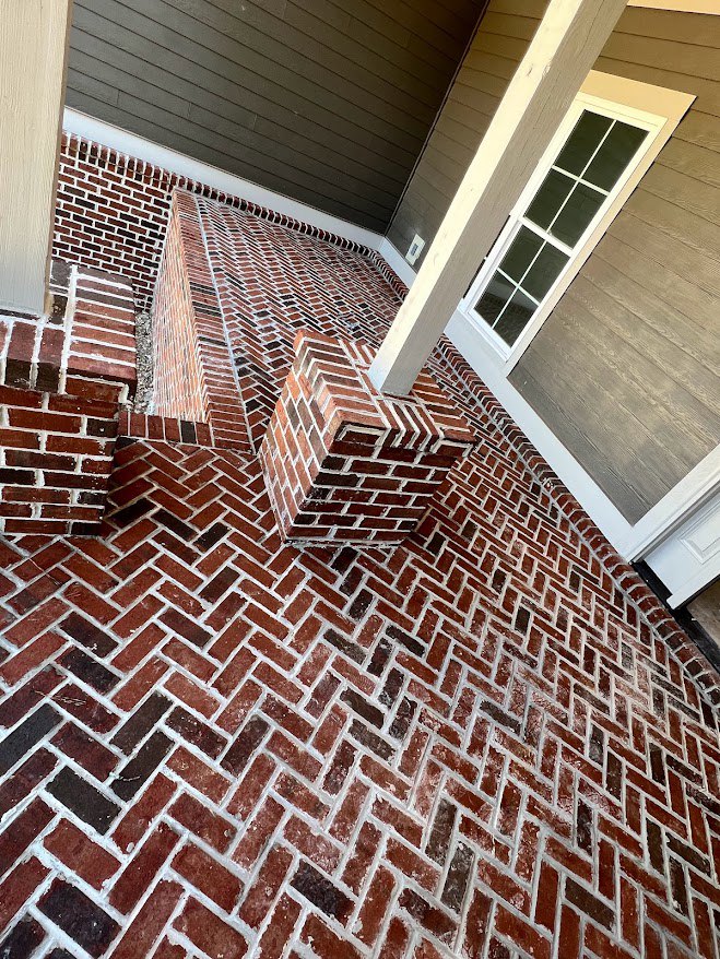 Brick porch with white pillars, brick chimney, window set in brick wall, close-up of wood board, symmetrical brickwork exterior