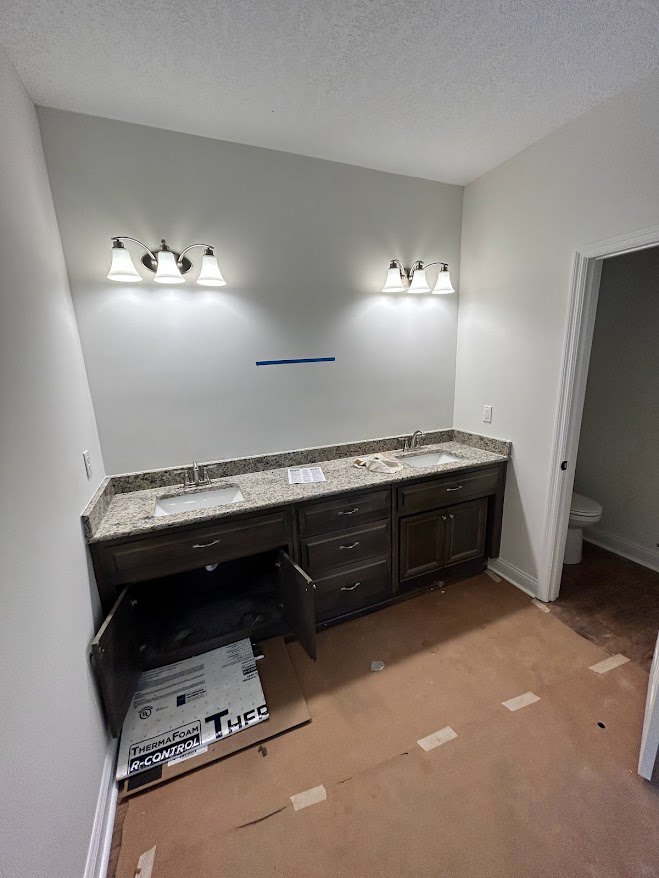 Bathroom with white porcelain sink, modern toilet, plaster walls, tile flooring, and ceiling-mounted light fixture with white shade