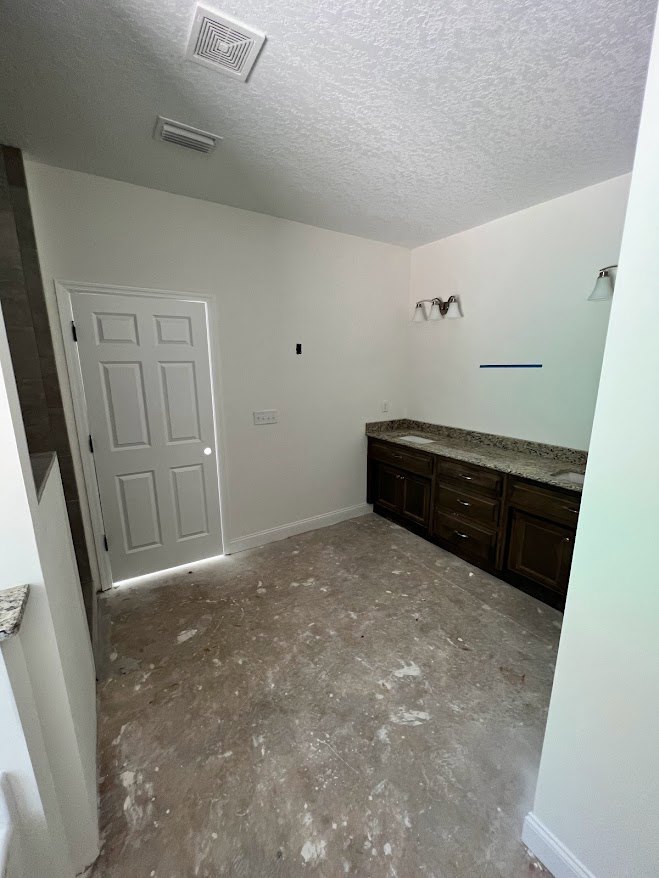 Bathroom with polished marble floor, marble sink countertop, white paneled door, ceiling vent, and built-in drawers under the vanity