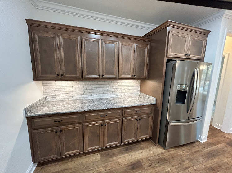 Granite countertop kitchen with stainless steel refrigerator, white cabinetry, and built-in appliances