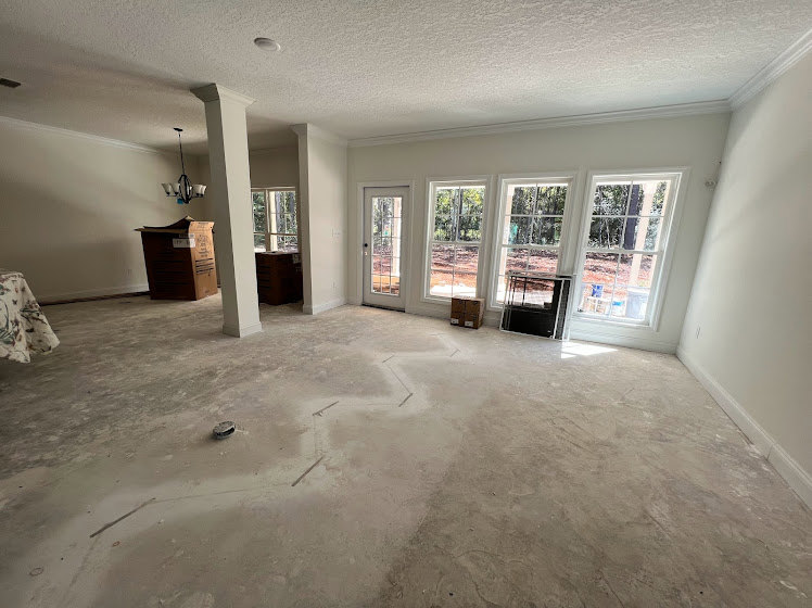 Bright room with white plaster walls, wood flooring, large windows, and a paneled door