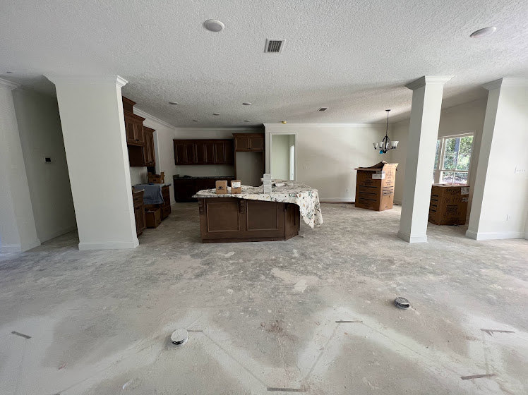 Basement room with plaster walls, wood table, built-in cabinets, and light-colored flooring