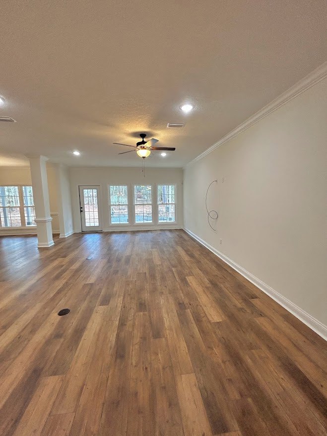 Ceiling fan with light fixture, hardwood floors, white walls, large window with outdoor view, glass-paneled door