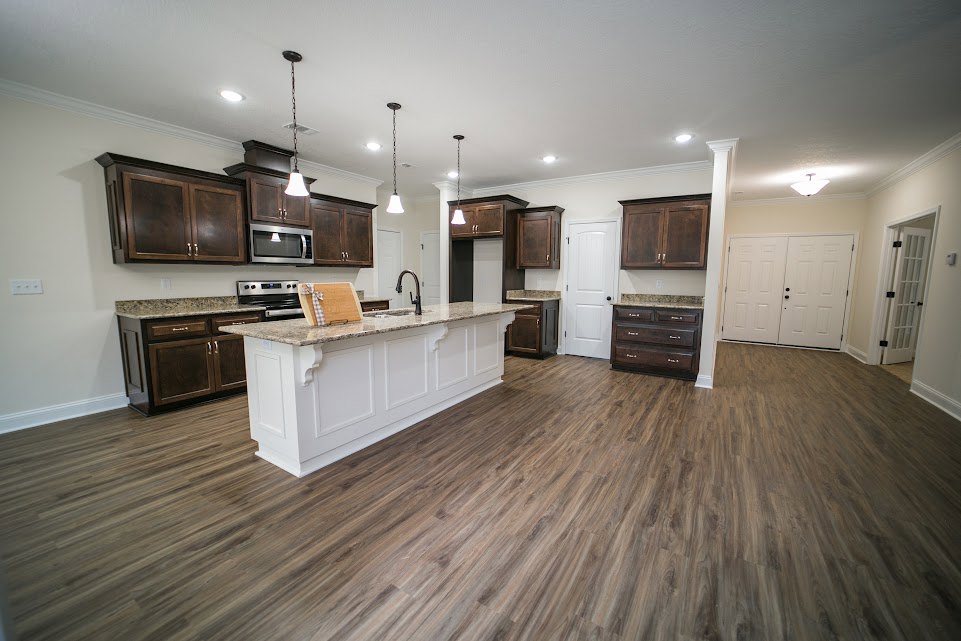 Kitchen featuring dark wood cabinets, white island with quartz countertop, wood flooring, white double doors with black handles, stainless steel appliances, and recessed ceiling