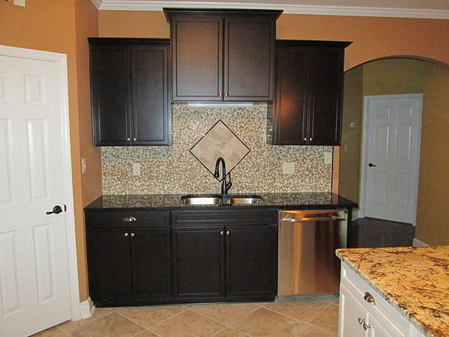 Kitchen with matte black cabinets, granite countertops, stainless steel sink, and tile backsplash