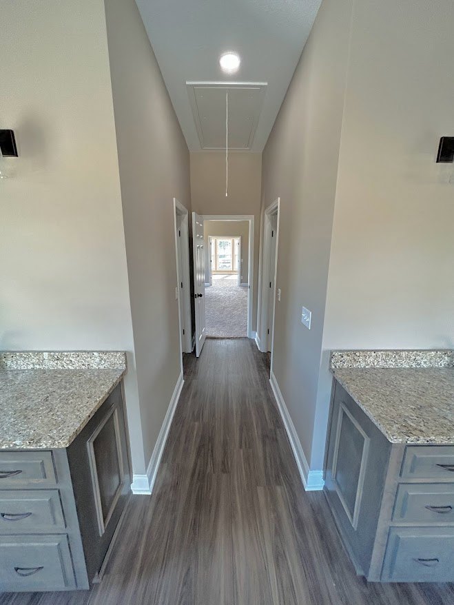 Long hallway with marble countertops, white cabinetry with drawers, large window, light laminate flooring, plaster walls, and decorative molding.
