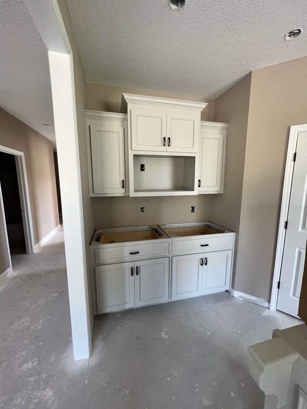 Kitchen with white shaker cabinets, light tile floor, stone countertop, and a hole in the wall near the sink area