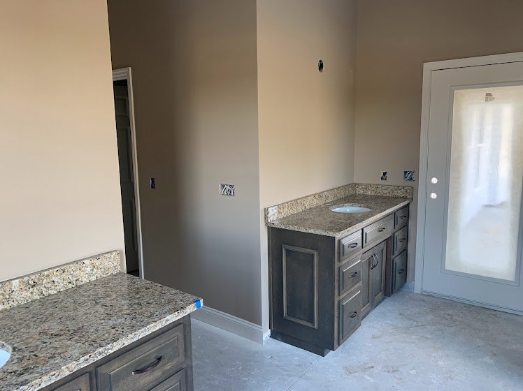 Granite countertop with marbled surface, undermount sink, chrome faucet, white cabinetry with drawers, tile floor, white door with frosted window