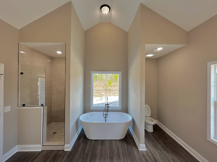 Modern bathroom featuring a freestanding tub, glass-enclosed shower, white square sink with metal faucet, light tile flooring, and neutral wall finishes.