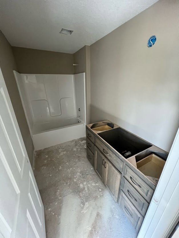 Bathroom featuring freestanding bathtub, light wood cabinetry with drawers, plaster walls, tile flooring, and recessed ceiling lighting