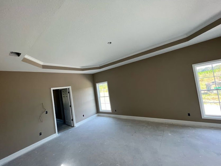 Bright room with smooth white ceiling, large window framed in white, light-colored walls, and view of green grass outside