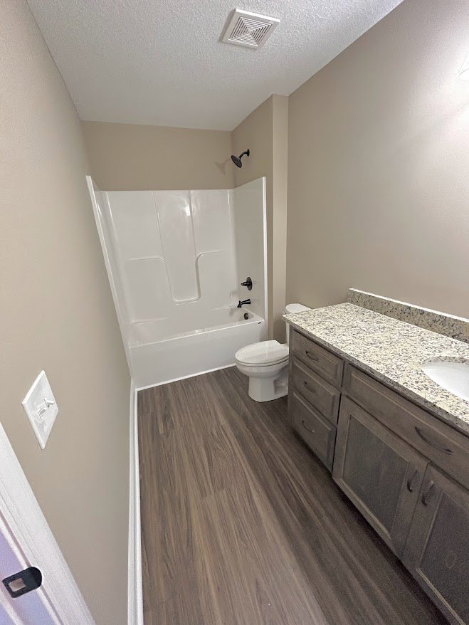Bathroom with white toilet, modern sink, tile flooring, light-colored walls, ceiling vent, and built-in cabinetry.