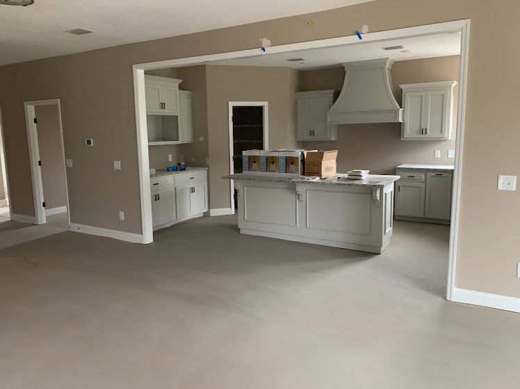 White cabinetry and matching white countertop in a modern kitchen with stainless steel sink, light-colored flooring, and neutral walls.