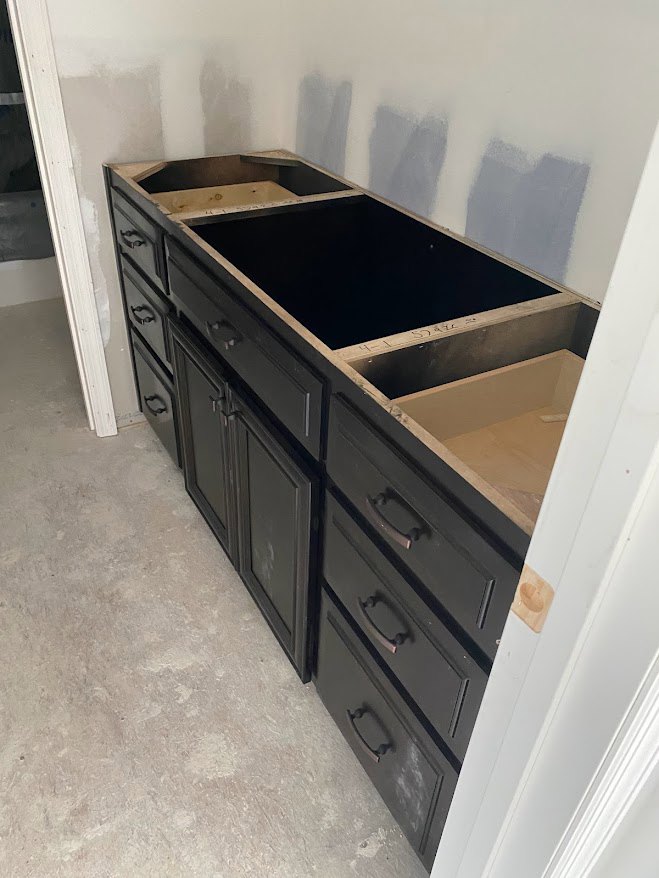 Modern kitchen with black cabinetry, wood drawers, and a sleek countertop featuring an integrated sink
