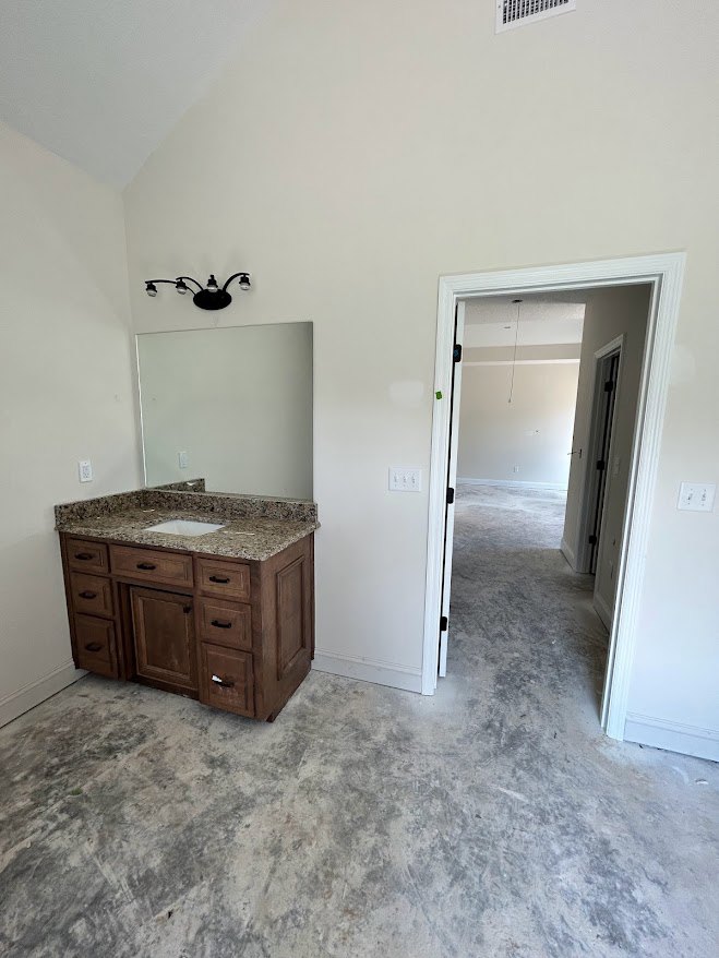 Bathroom with marble countertop, undermount sink, white cabinetry with drawers, large wall mirror, open door revealing carpeted floor in adjacent room