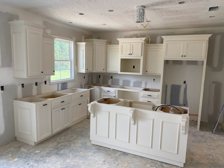 White kitchen cabinets with stainless steel appliances, light stone countertops, tile backsplash, and wood flooring