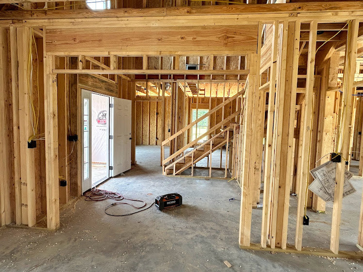 Exposed wooden beams and framing with unfinished walls and visible insulation inside a residential home under construction