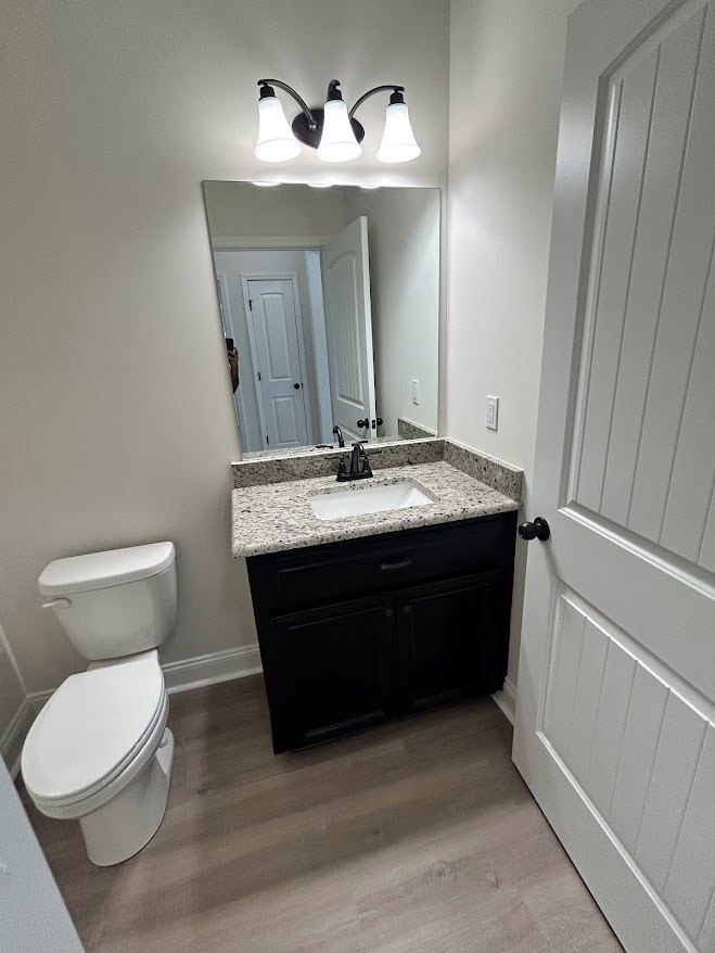 Bathroom with white toilet, white sink featuring black faucet, light tile walls, and wall-mounted mirror