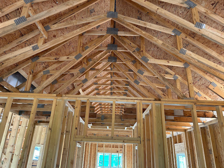 Exposed wood framing and beams with insulation visible, close-up view of window opening in unfinished interior