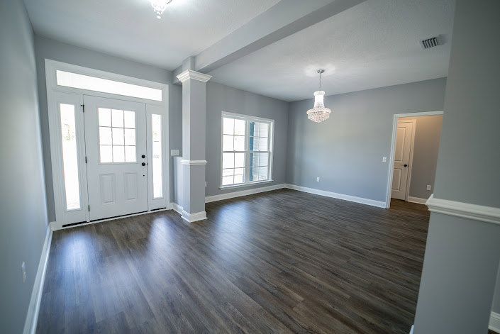 Room featuring hardwood flooring, white plaster walls, and a wooden door