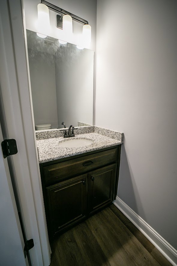White bathroom vanity with undermount sink, chrome faucet, large framed mirror, tiled backsplash, built-in cabinetry and drawers, window above bathtub, neutral wall tiles