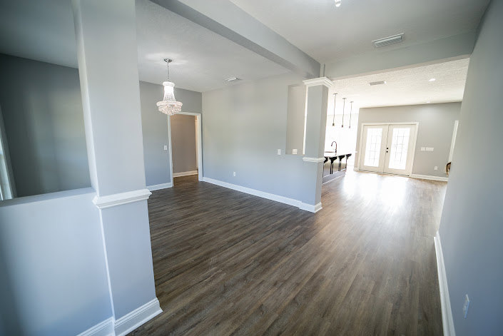 Wood flooring room with white plaster walls, paneled door, and flat ceiling.