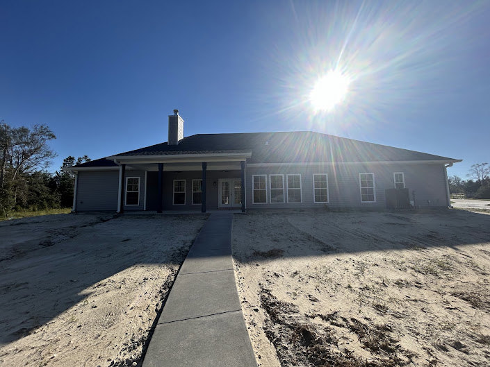 Two-story house with light siding, attached garage, paved driveway, manicured lawn, and clear blue sky