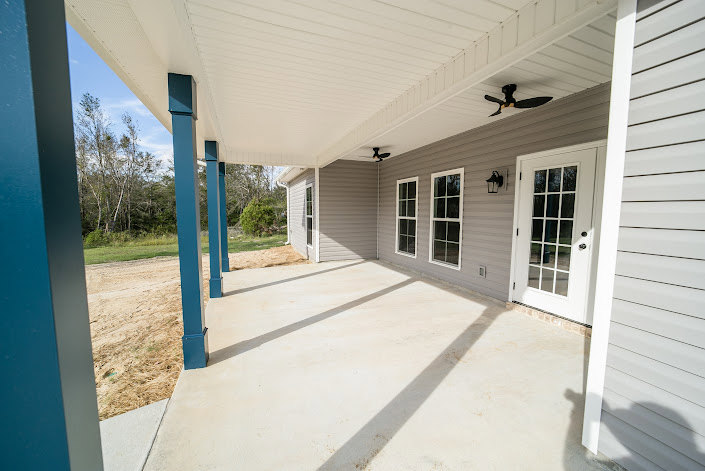 Front porch with ceiling fan, composite siding, shaded entry, and visible door under clear sky