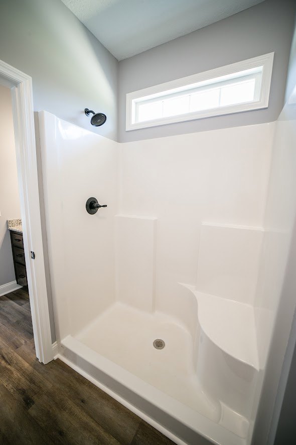 Glass-enclosed shower with white tile walls, chrome fixtures, and built-in niche beside freestanding bathtub in modern bathroom