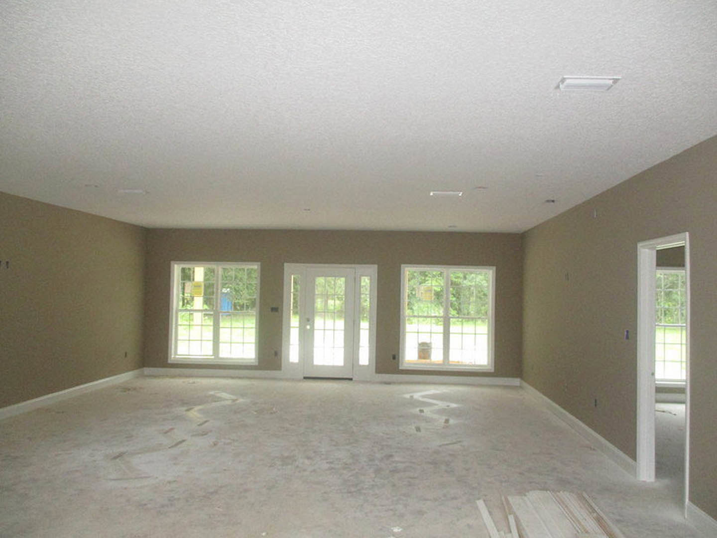 White-paneled door with glass panes, adjacent white-framed window, light-colored flooring, smooth plaster walls, and ceiling in a bright interior room.