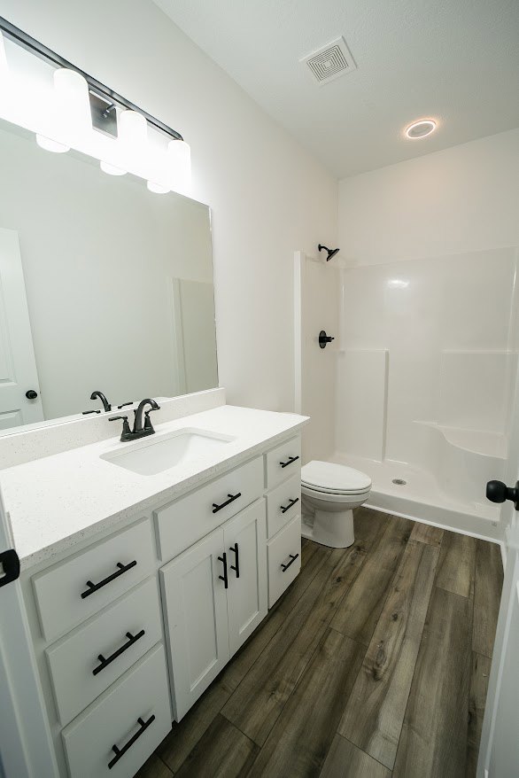 Modern bathroom featuring a white toilet, white countertop with black faucet, rectangular sink, light tile flooring, and neutral cabinetry.