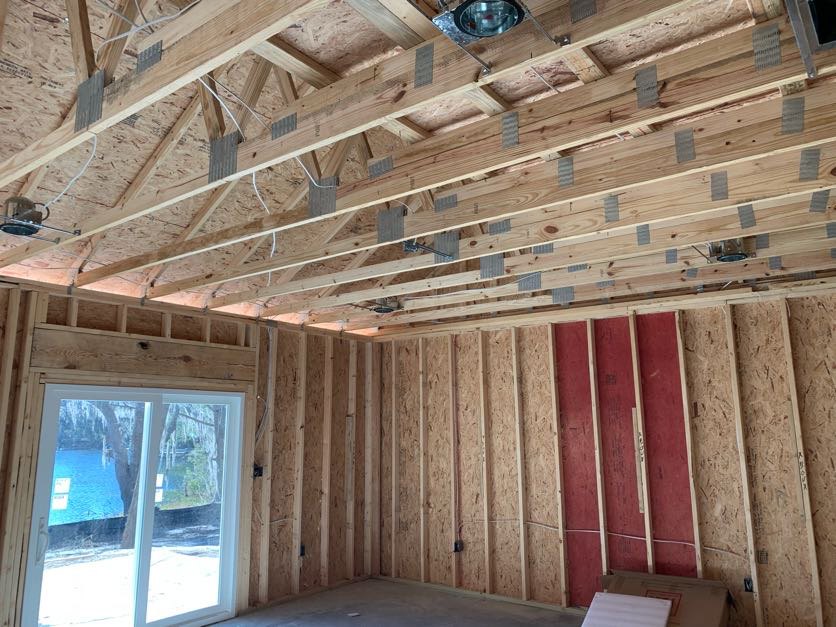 Living room with exposed wood ceiling beams, large window, and sliding glass door overlooking a river