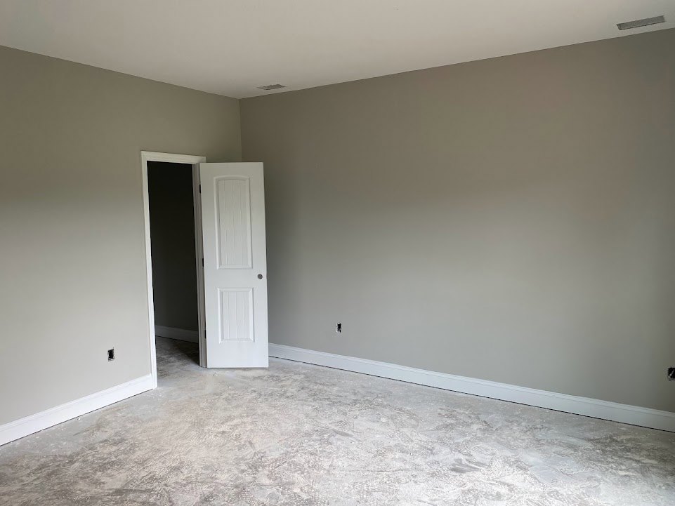 White interior room featuring an open white door with a round knob, white floor and ceiling, contrasting black and white walls, and a white door frame against a dark background.