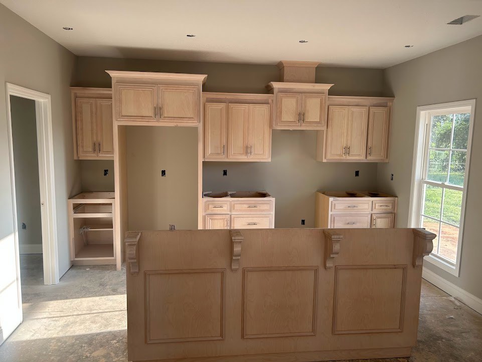 Kitchen with natural wood cabinets, white-framed window above sink, wood-paneled wall, open shelving, and close-up views of drawers and cabinet hardware