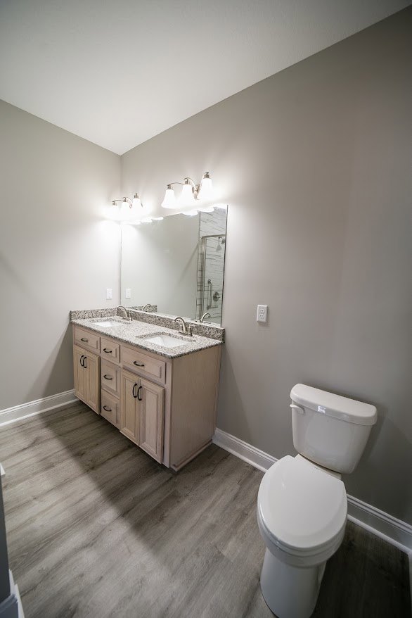 Bathroom with white toilet, closed lid, white sink, chrome faucet, light tile flooring, neutral wall tiles, modern plumbing fixtures